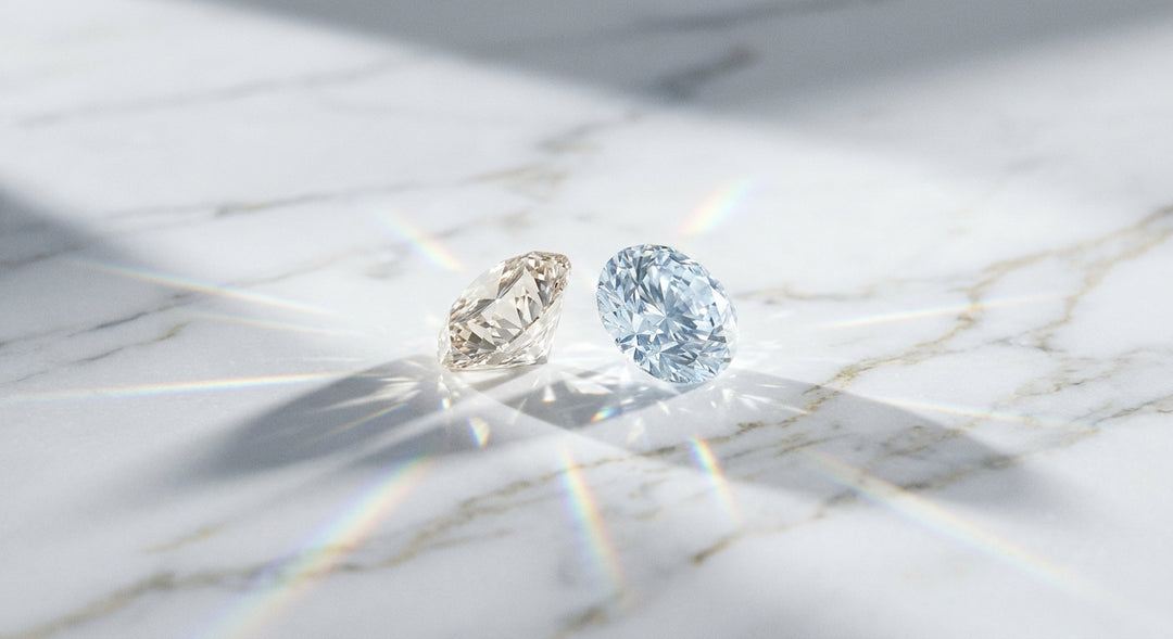 Two sparkling diamonds resting on a white marble surface, casting delicate light refractions, representing the comparison between lab-grown and natural diamonds.
